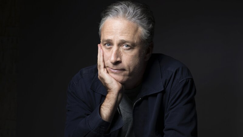 man with gray hair resting hand on face