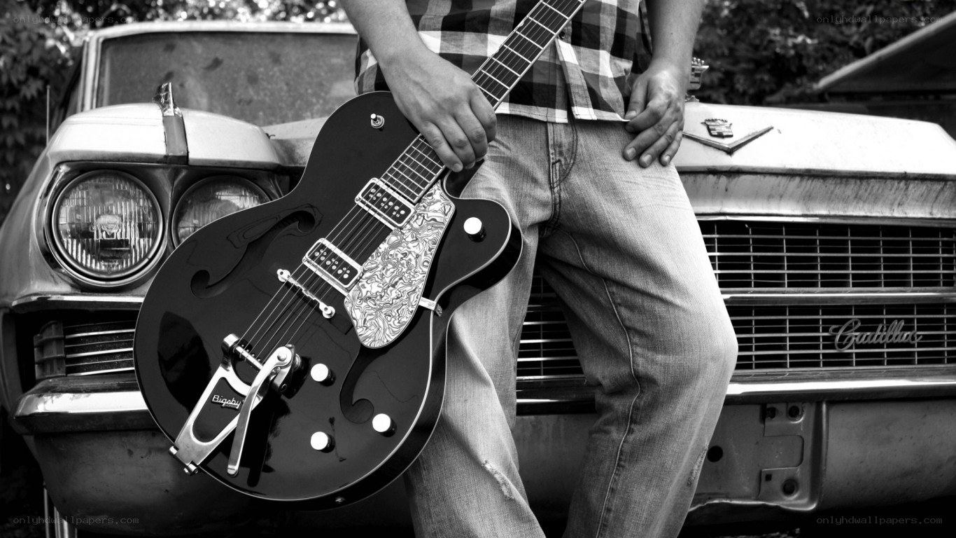 Man with guitar by classic car
