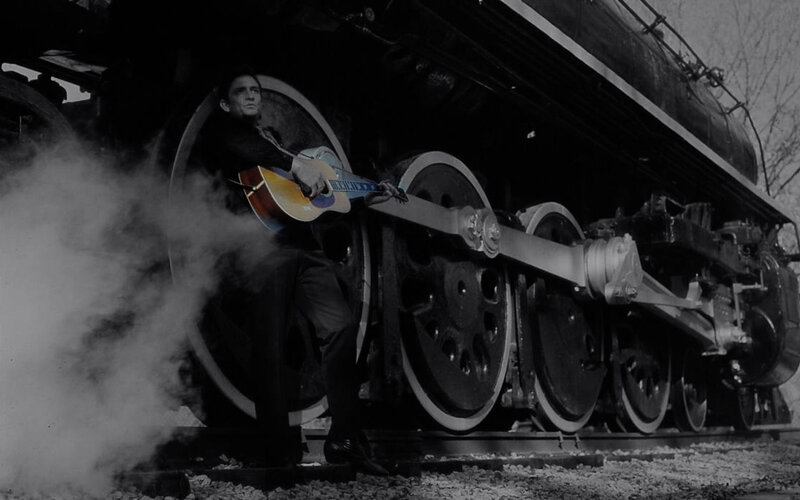 Man with guitar by steam train