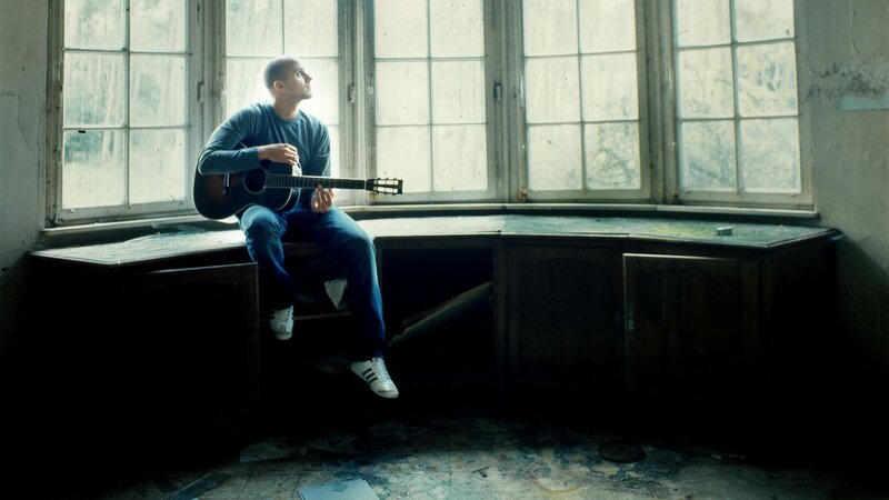 Man with guitar by window