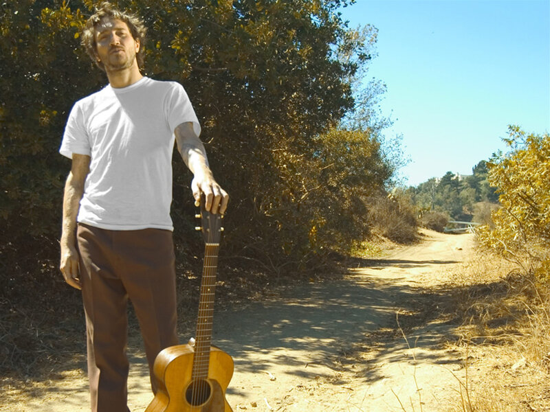 Man with guitar on dirt path