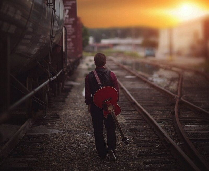 Man with Guitar on Train Tracks