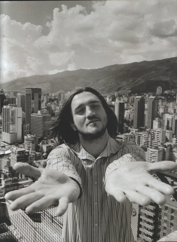 man with hands outstretched on rooftop