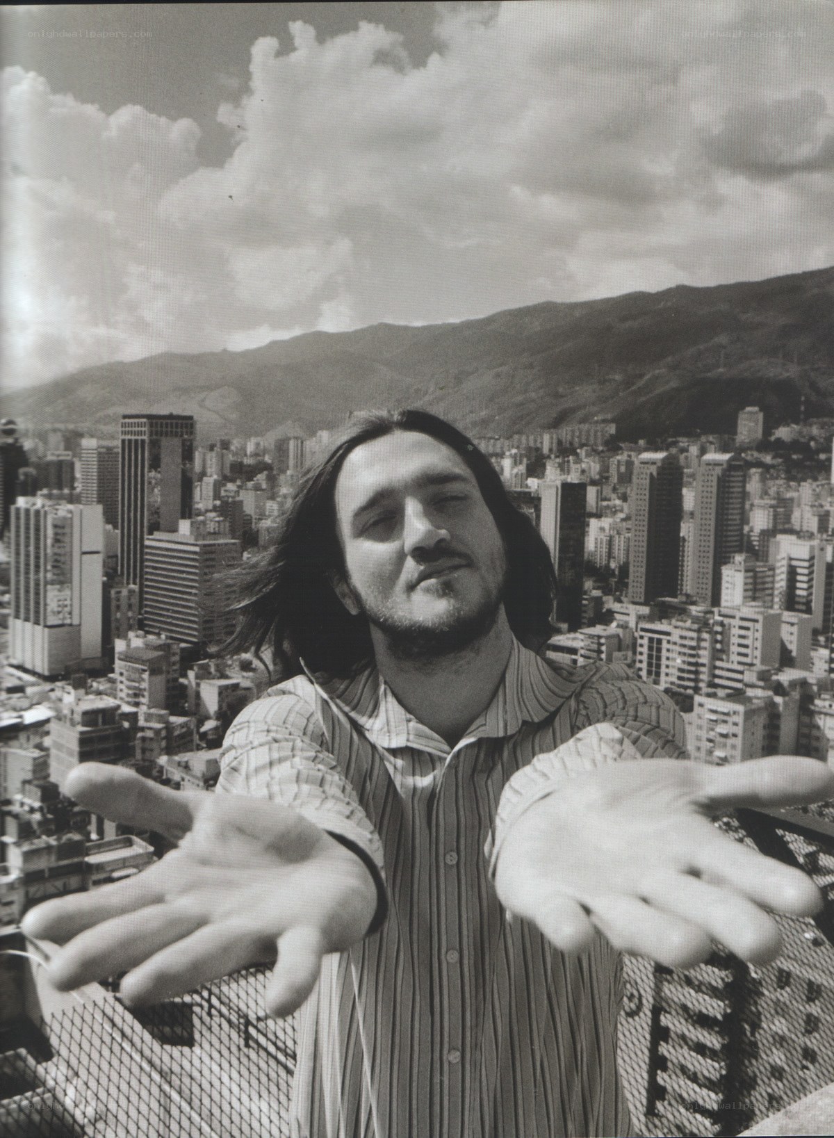 man with hands outstretched on rooftop