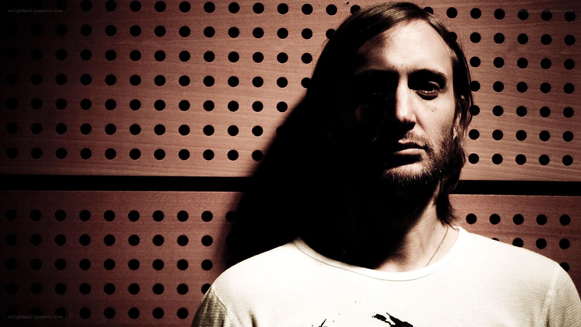 man with long hair against perforated wall