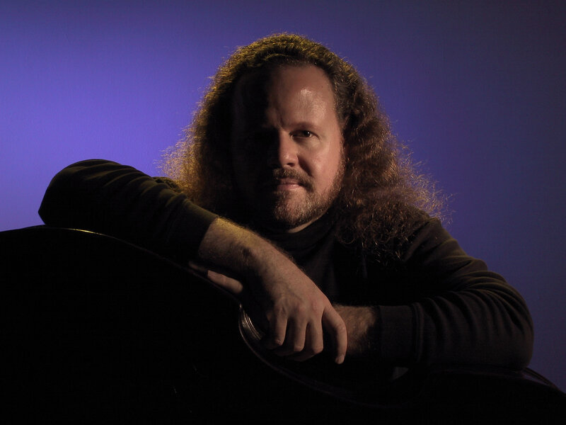 man with long hair and guitar