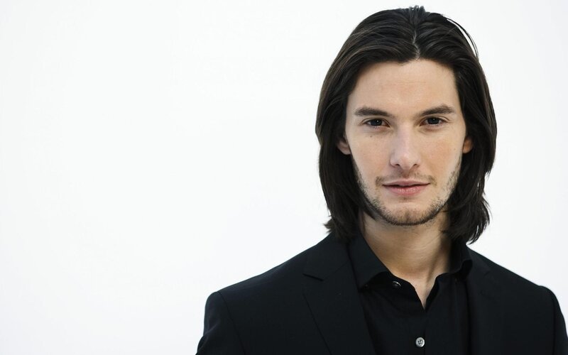man with long hair in black suit