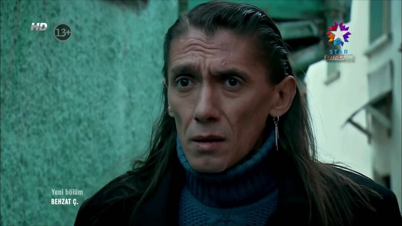 man with long hair in blue turtleneck