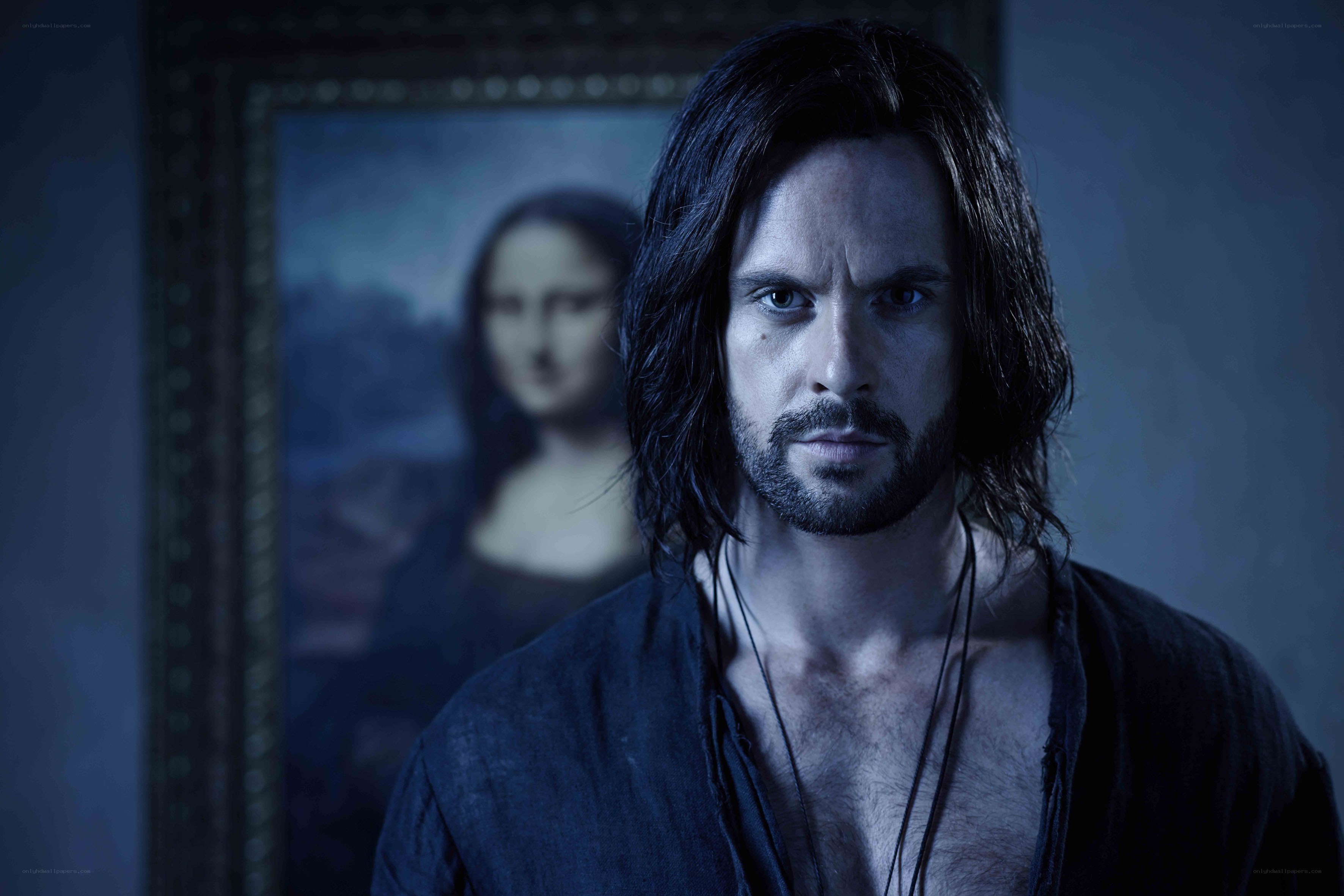 man with long hair in front of painting