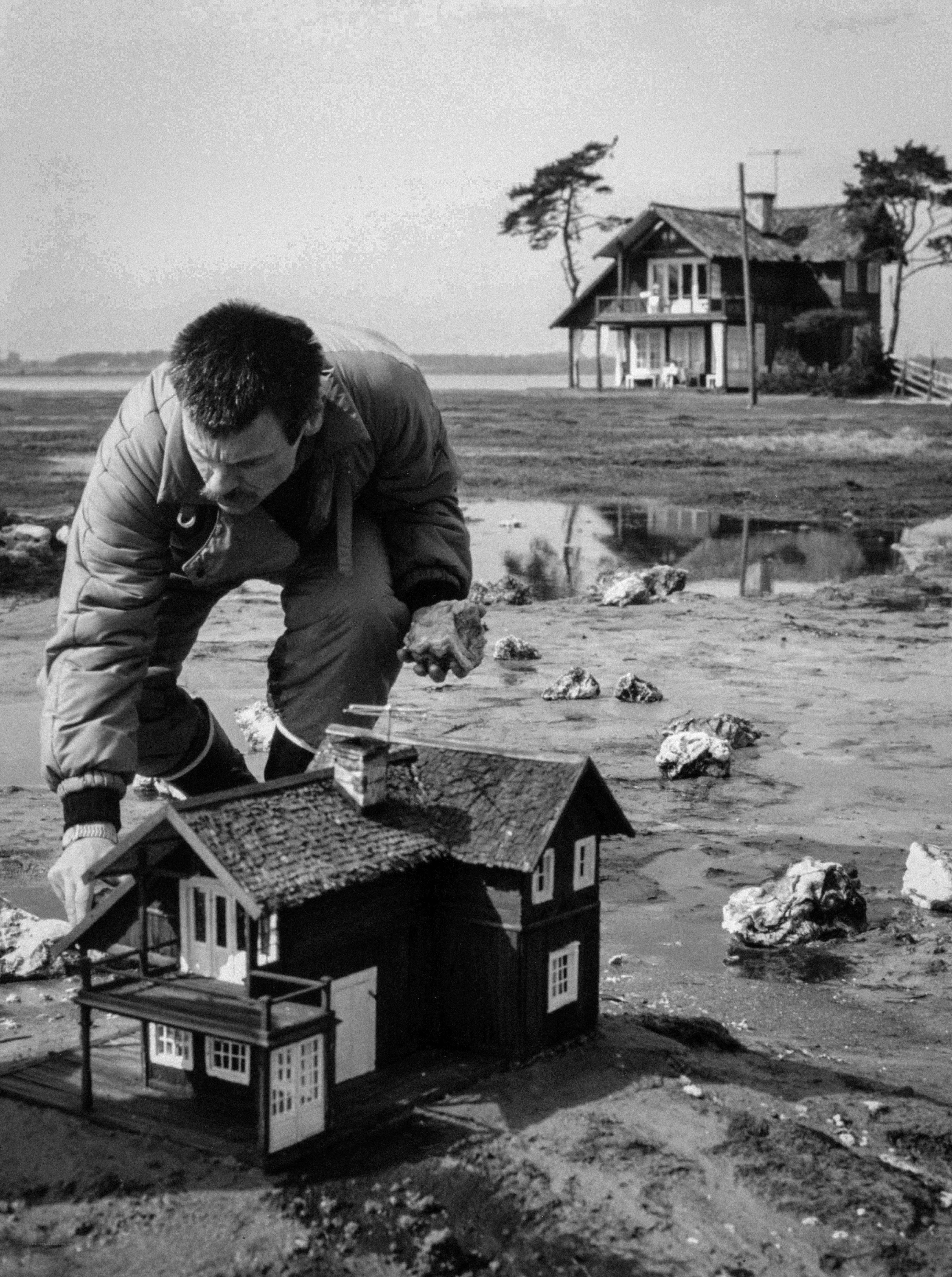 Man with model house on beach