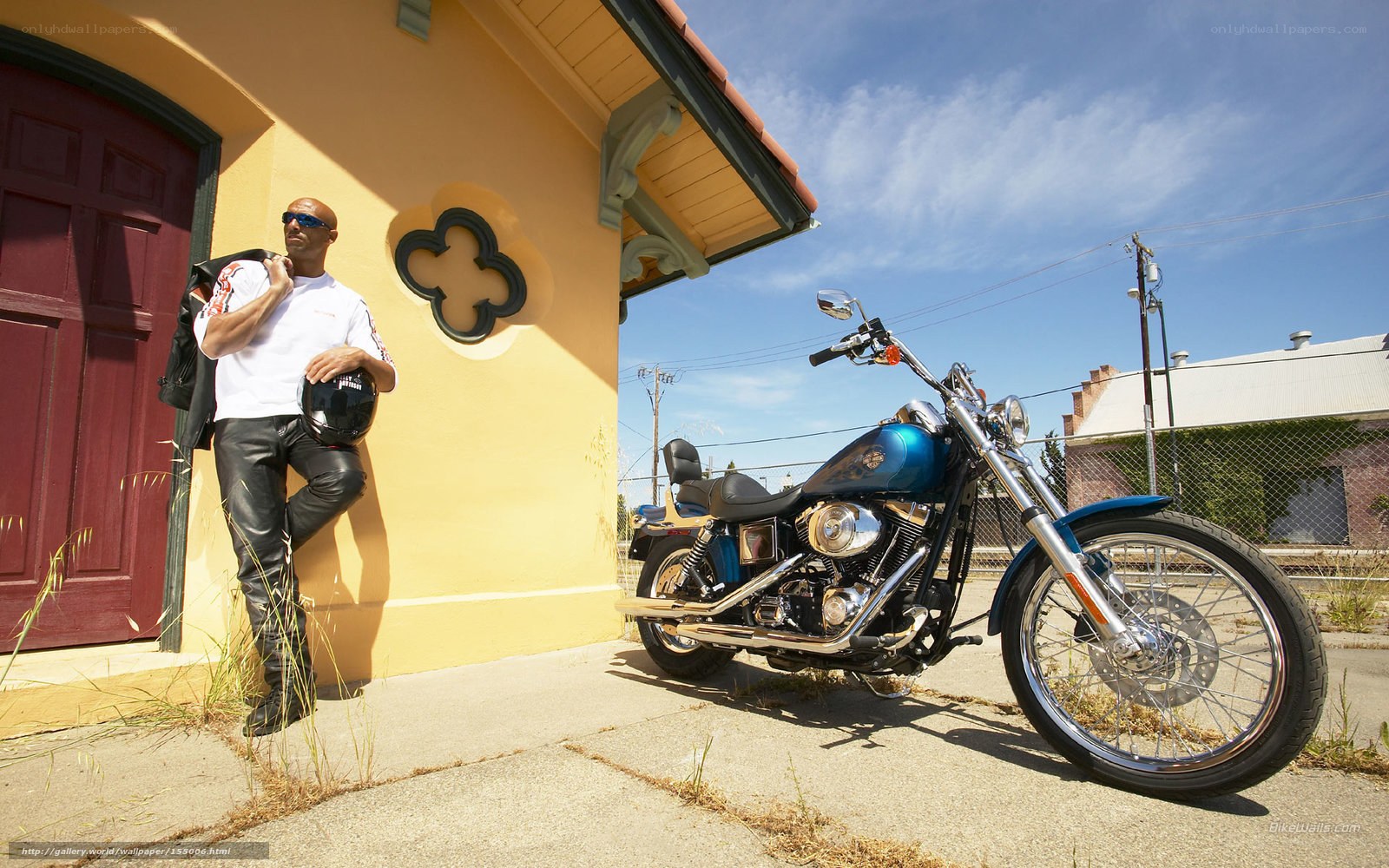 Man with motorcycle by building
