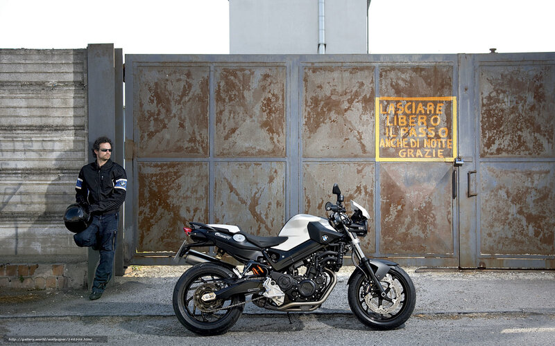 Man with motorcycle by gate