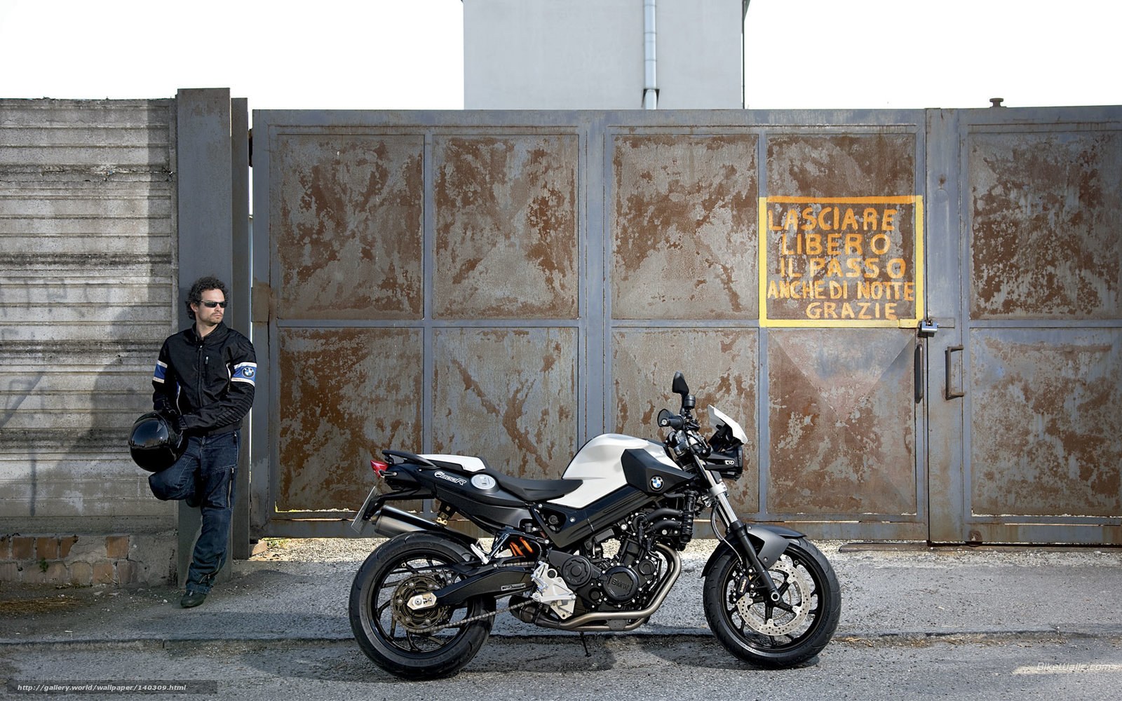 Man with motorcycle by gate
