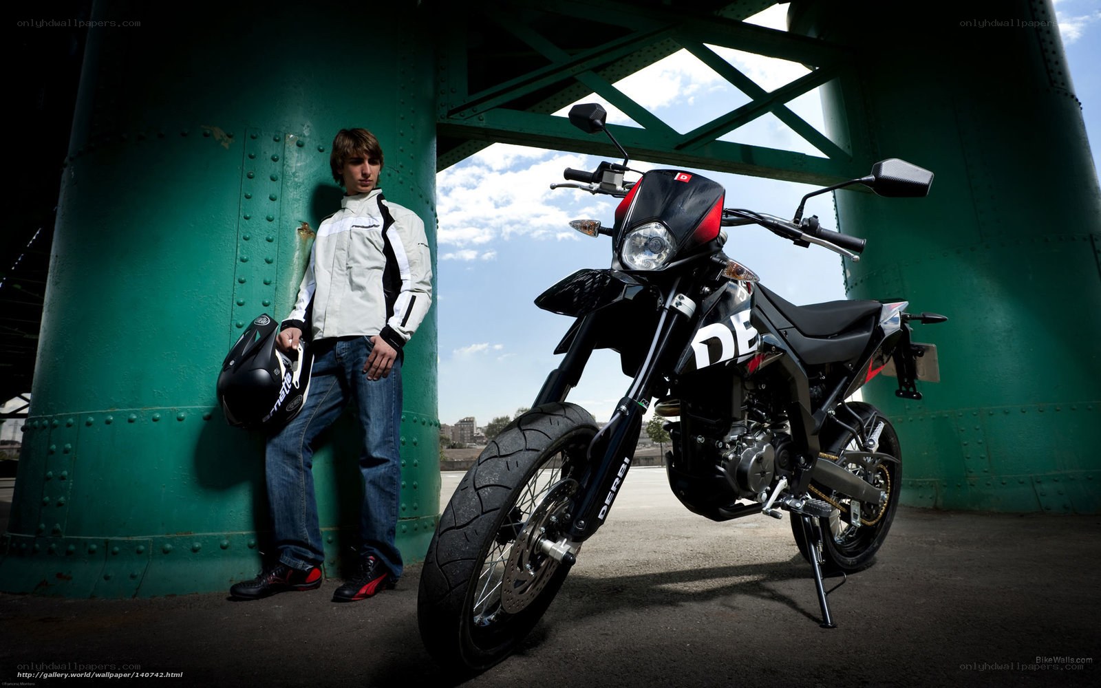 Man with motorcycle under bridge