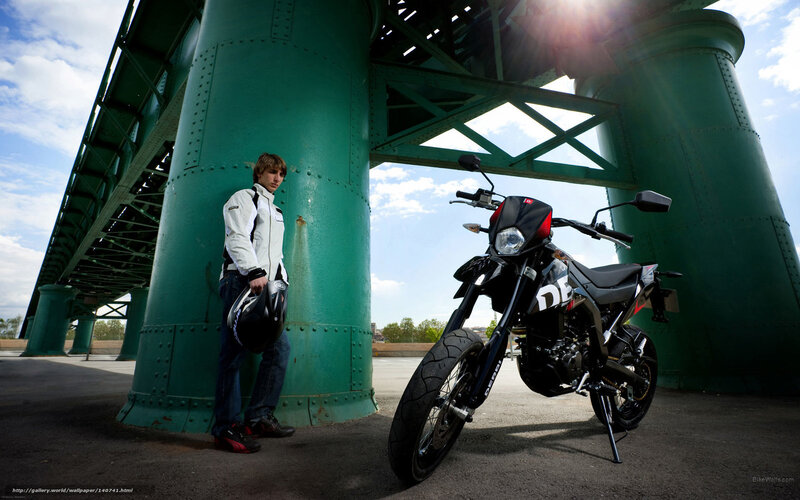 Man with motorcycle under bridge