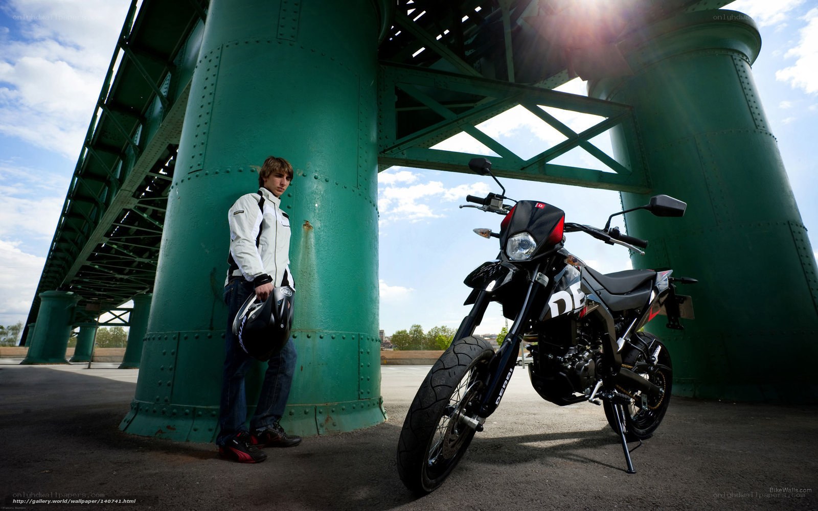 Man with motorcycle under bridge