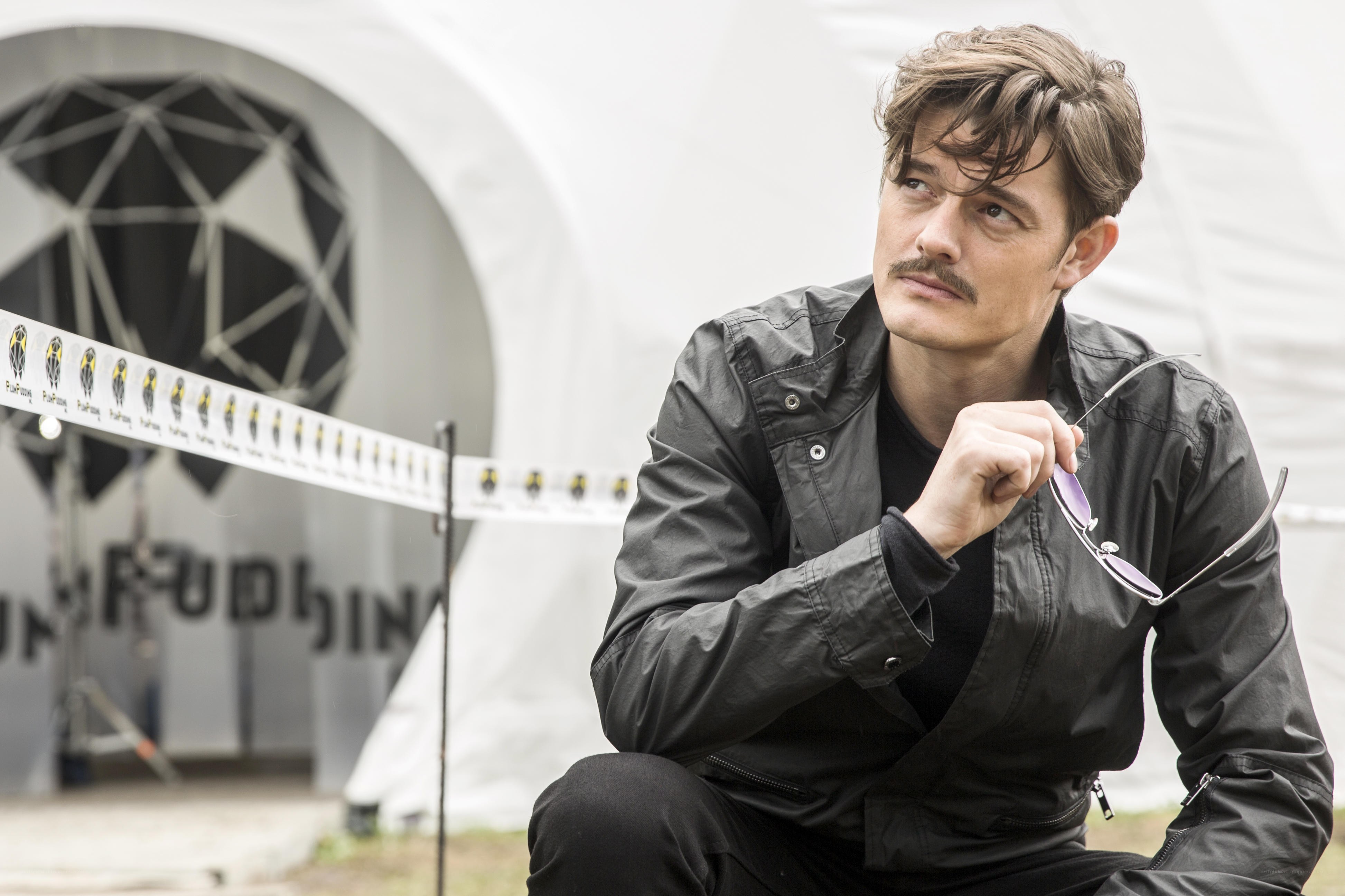 Man with mustache holding sunglasses