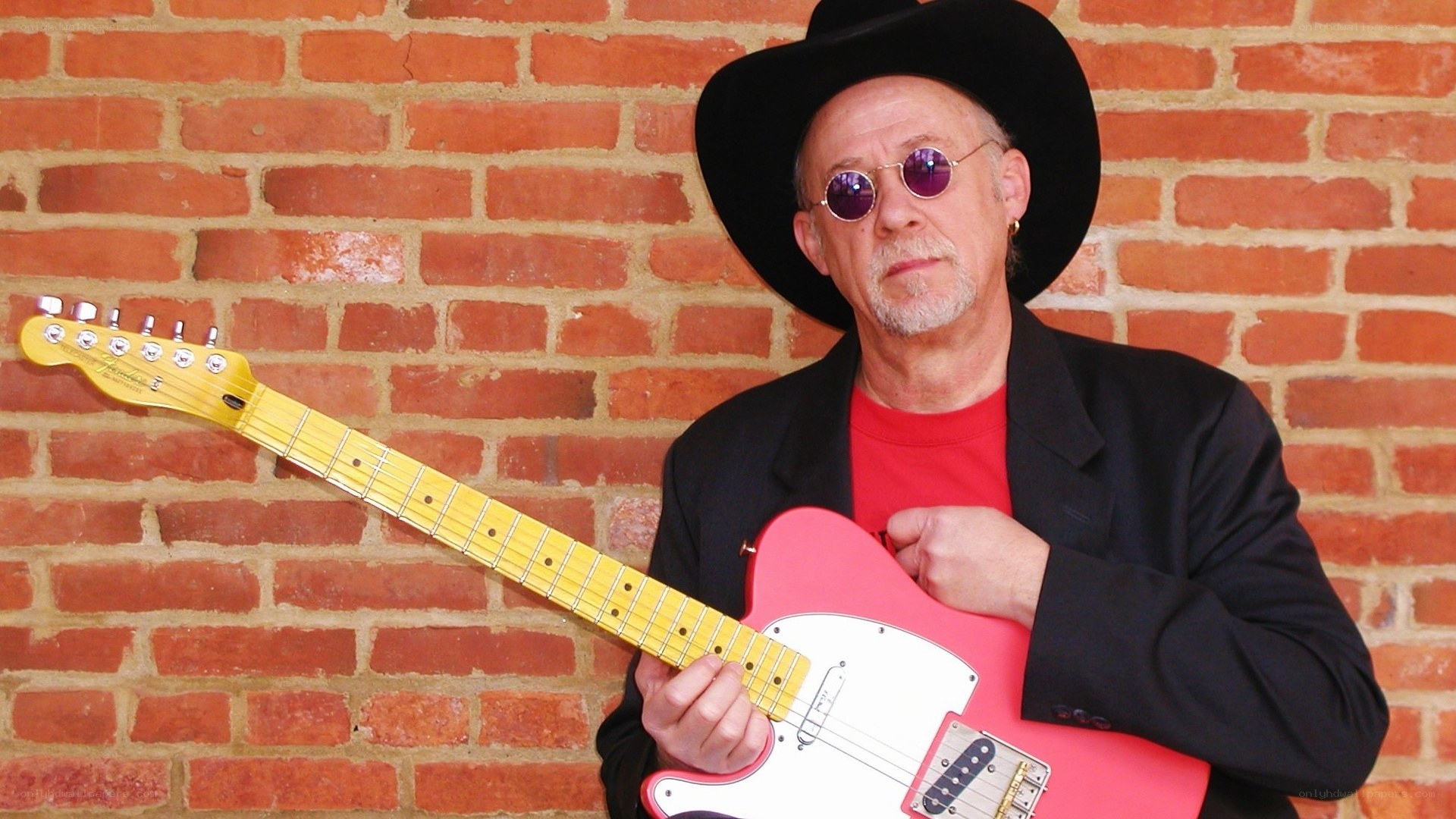 Man with pink guitar and hat