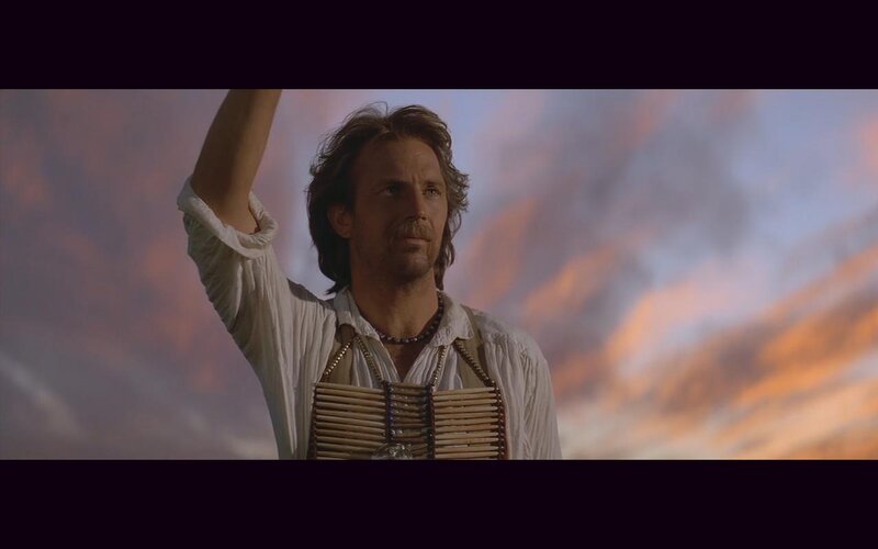 man with raised arm at sunset