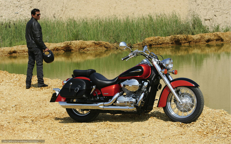 Man with red motorcycle by pond