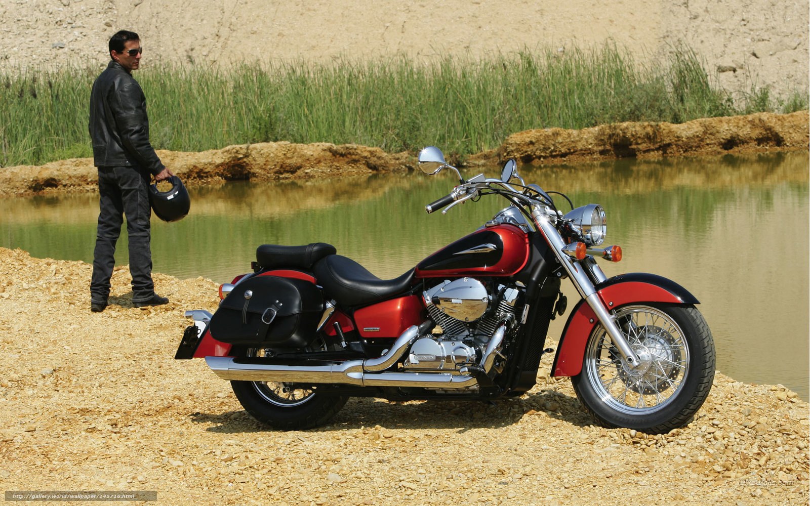 Man with red motorcycle by pond