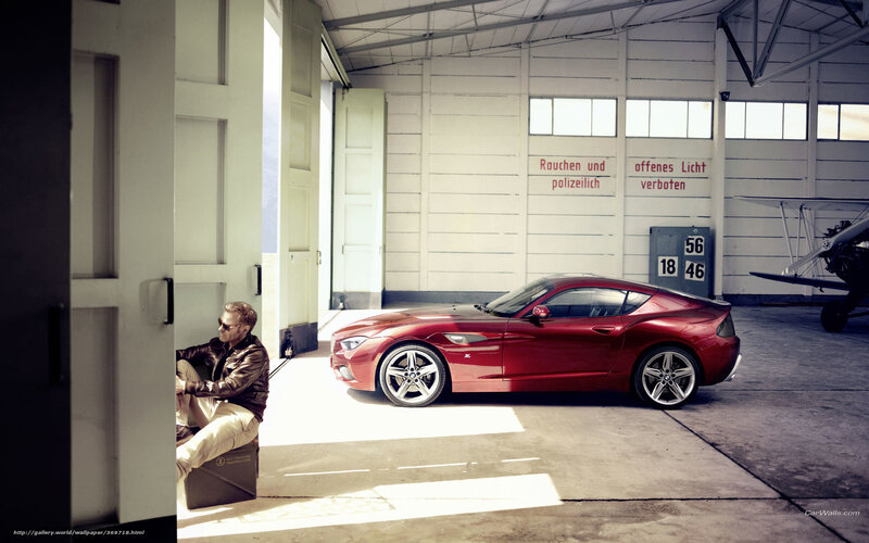 Man with red sports car in hangar