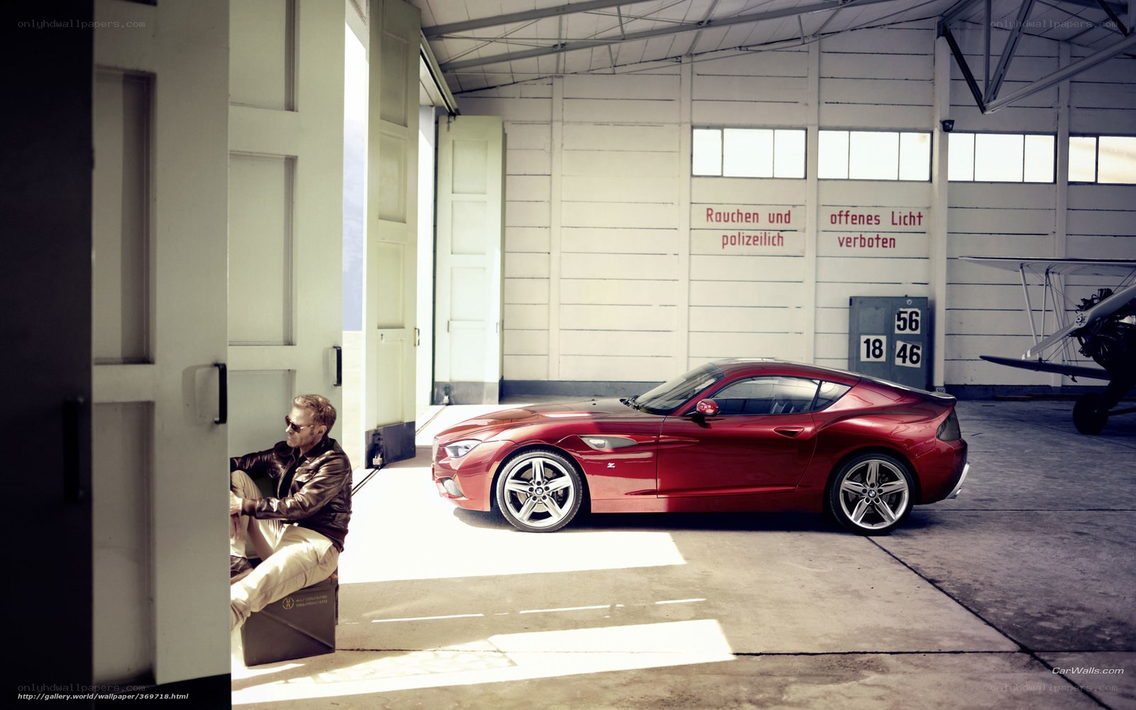 Man with red sports car in hangar