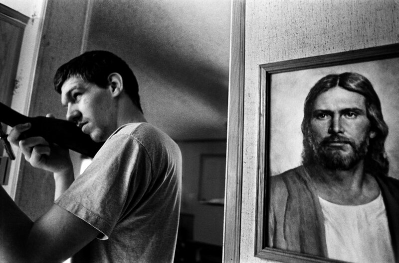 Man with rifle near Jesus portrait