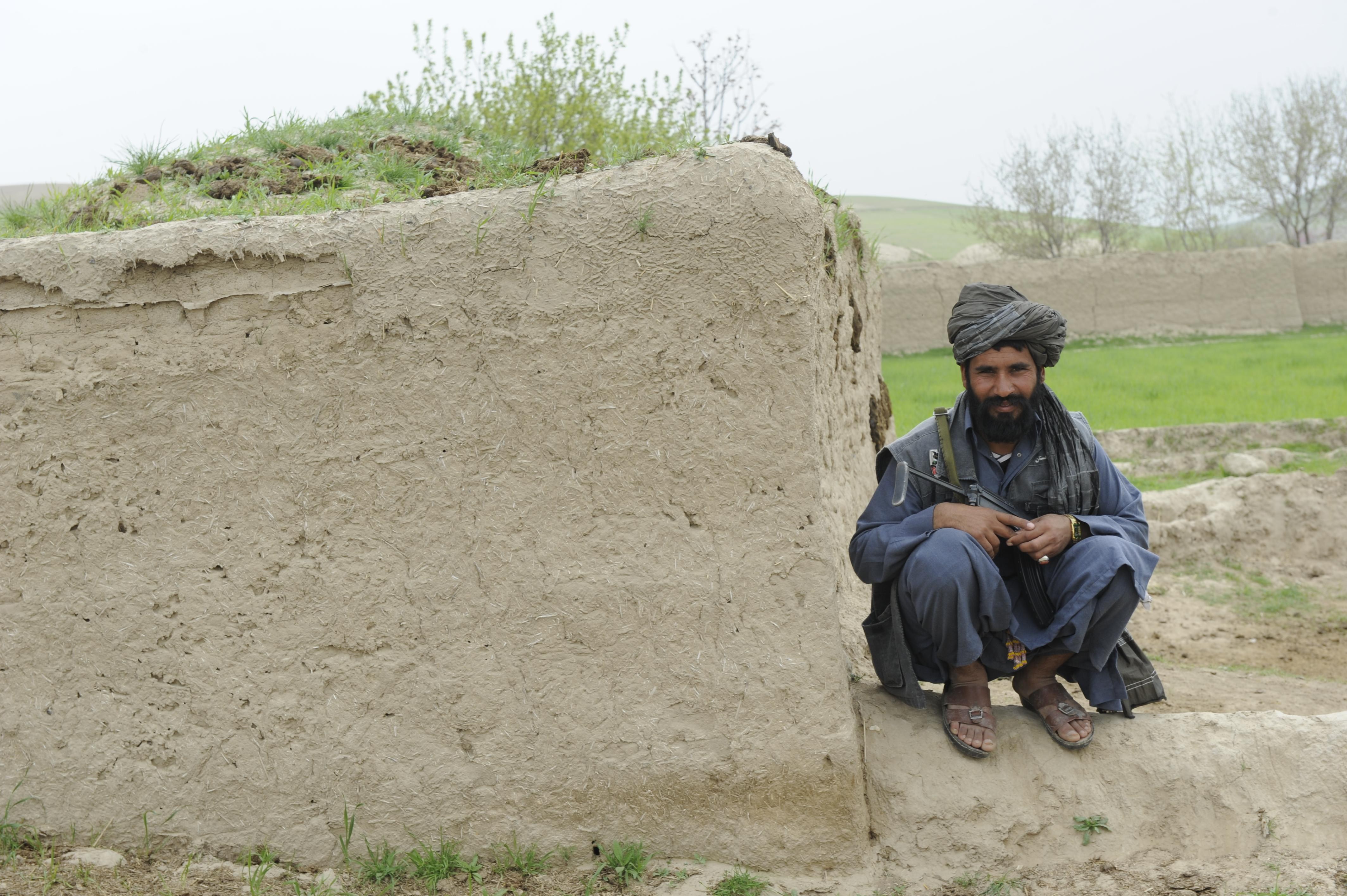 Man with rifle near mud wall