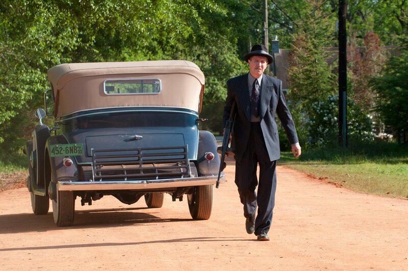 Man with rifle walking on dirt road