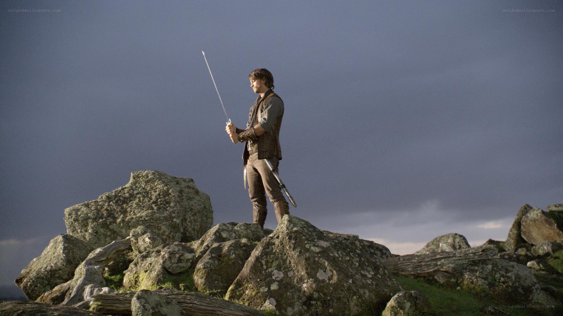 Man with sword on rocky hill