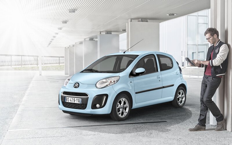 Man with tablet next to light blue car