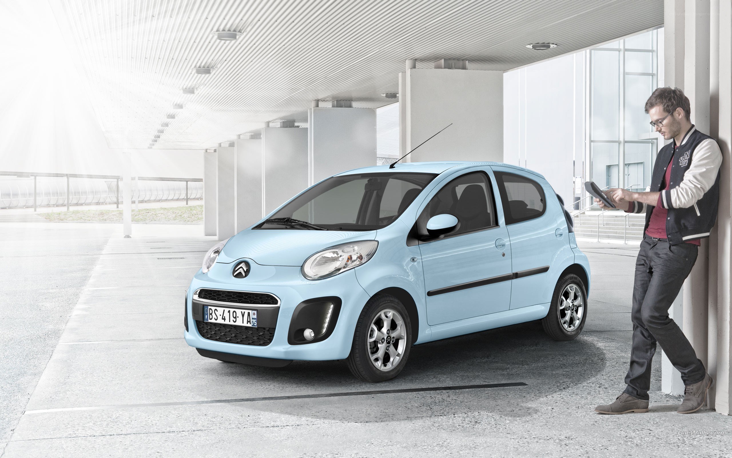 Man with tablet next to light blue car