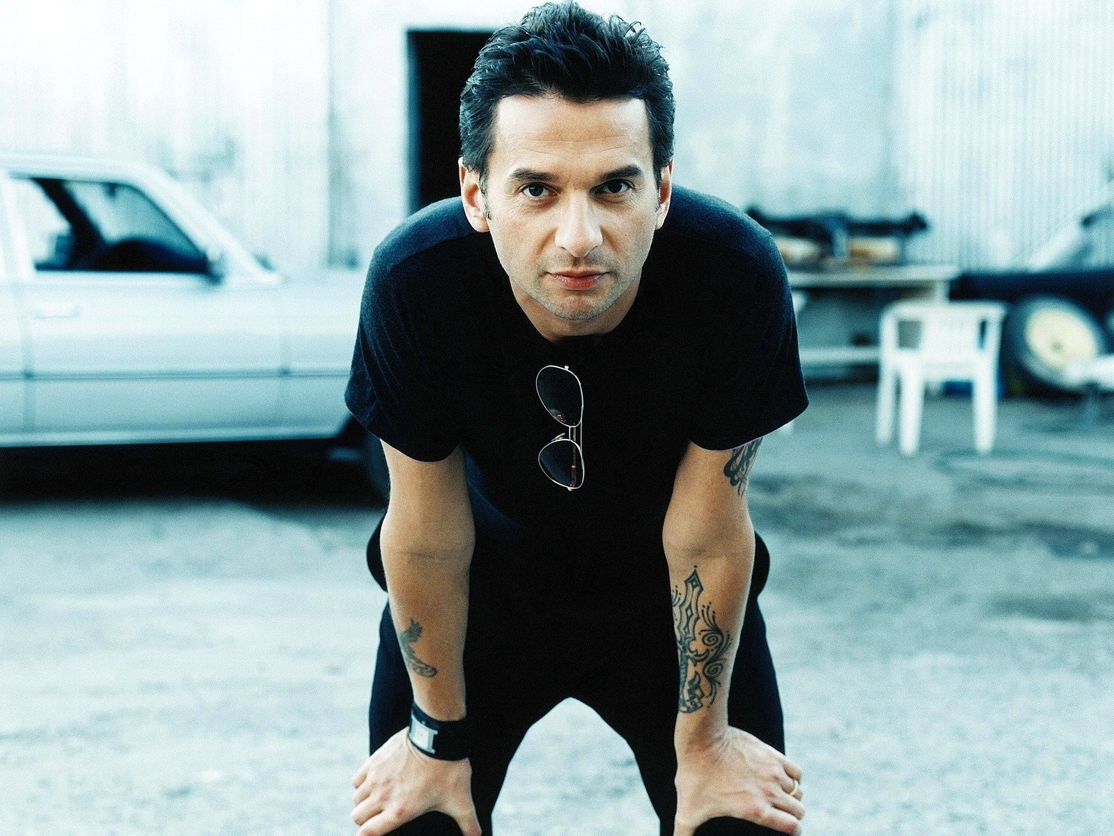 man with tattoos leaning forward