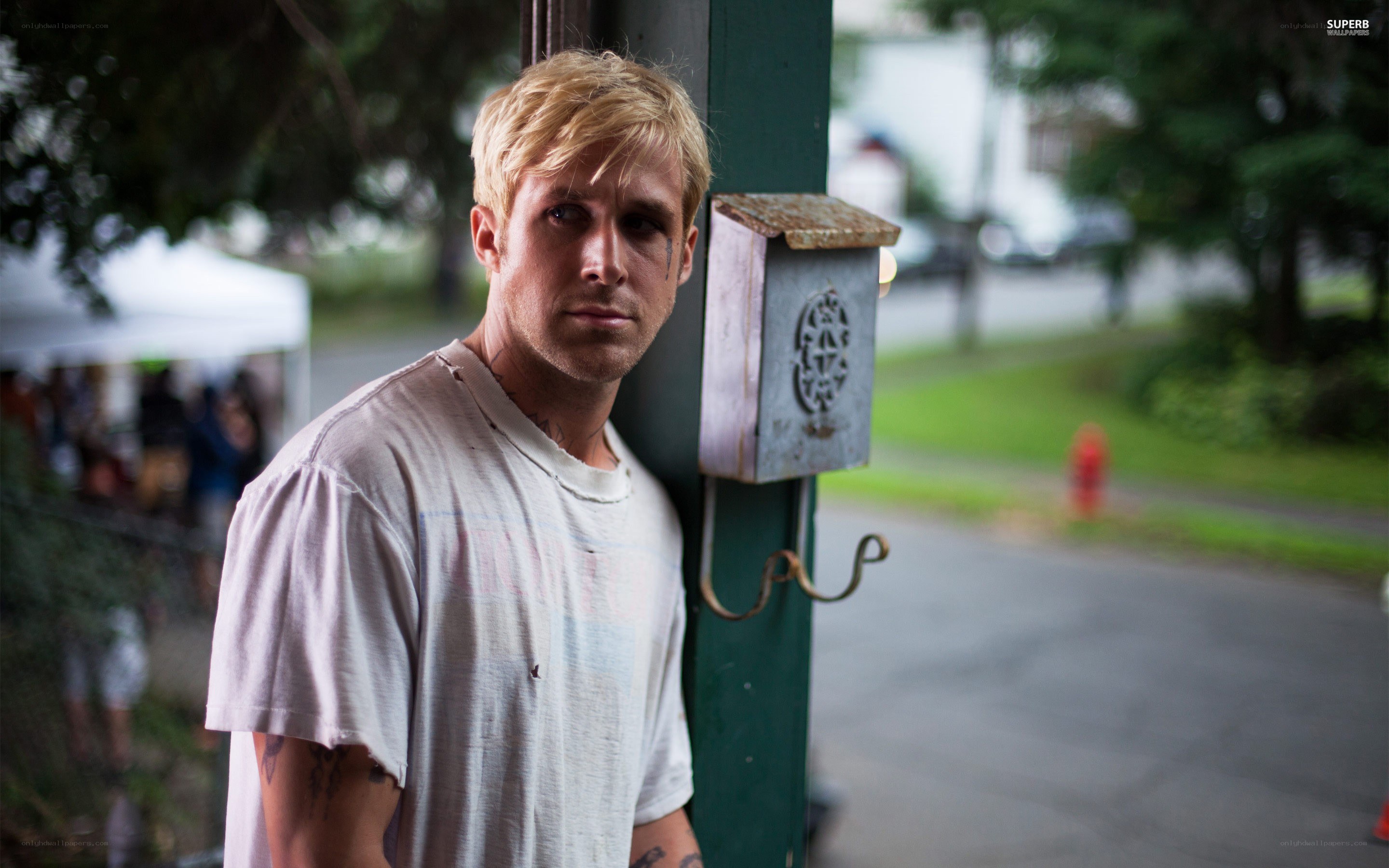 man with tattoos leaning on pole