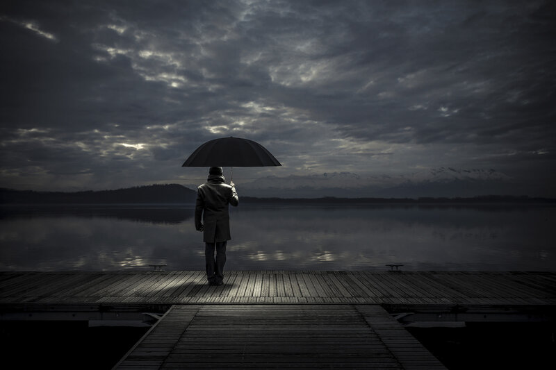 Man with umbrella on dock