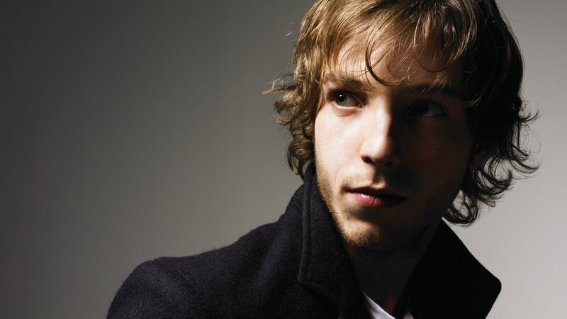 man with wavy hair in coat