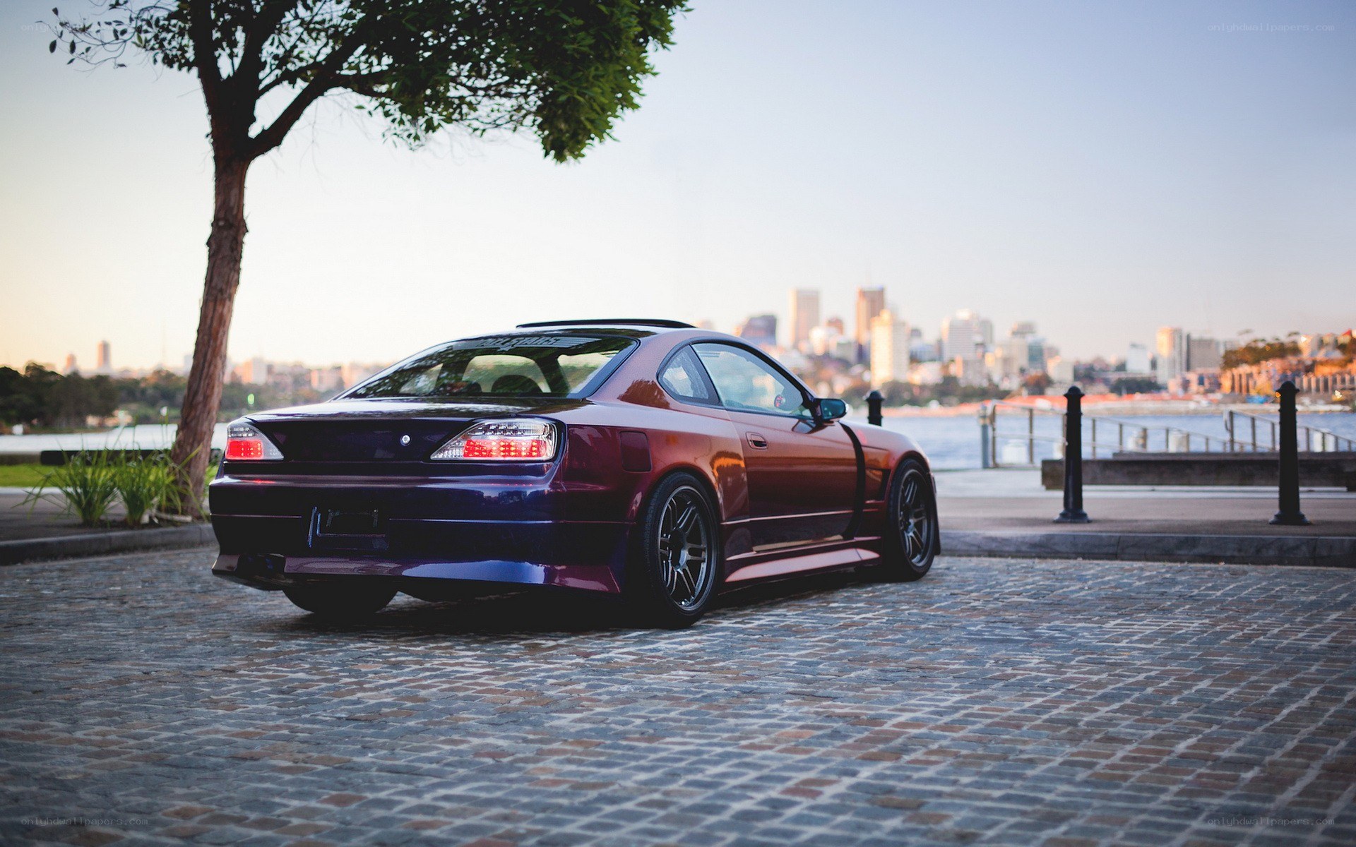maroon coupe on cobblestones