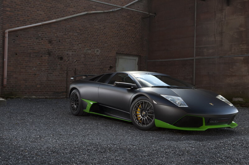 Matte Black Sports Car — Dramatic, Photograph, Brick Wall, Gravel Ground, Pipe