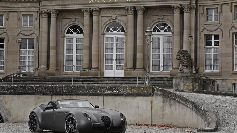 Matte black sports car in front of a mansion