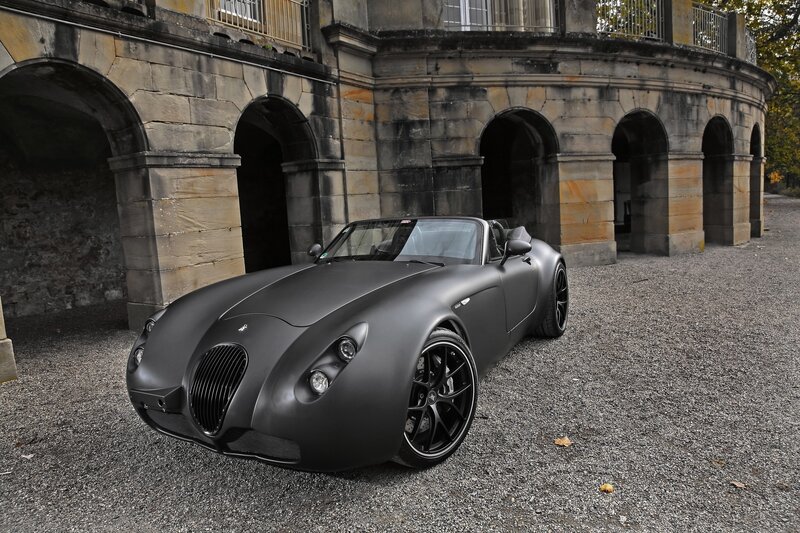 Matte black sports car in front of stone building