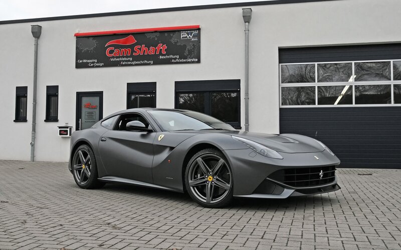 Matte gray Ferrari F12 parked outside shop