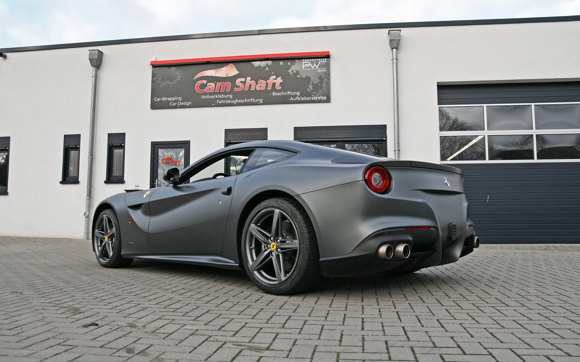 Matte gray Ferrari parked outside a shop