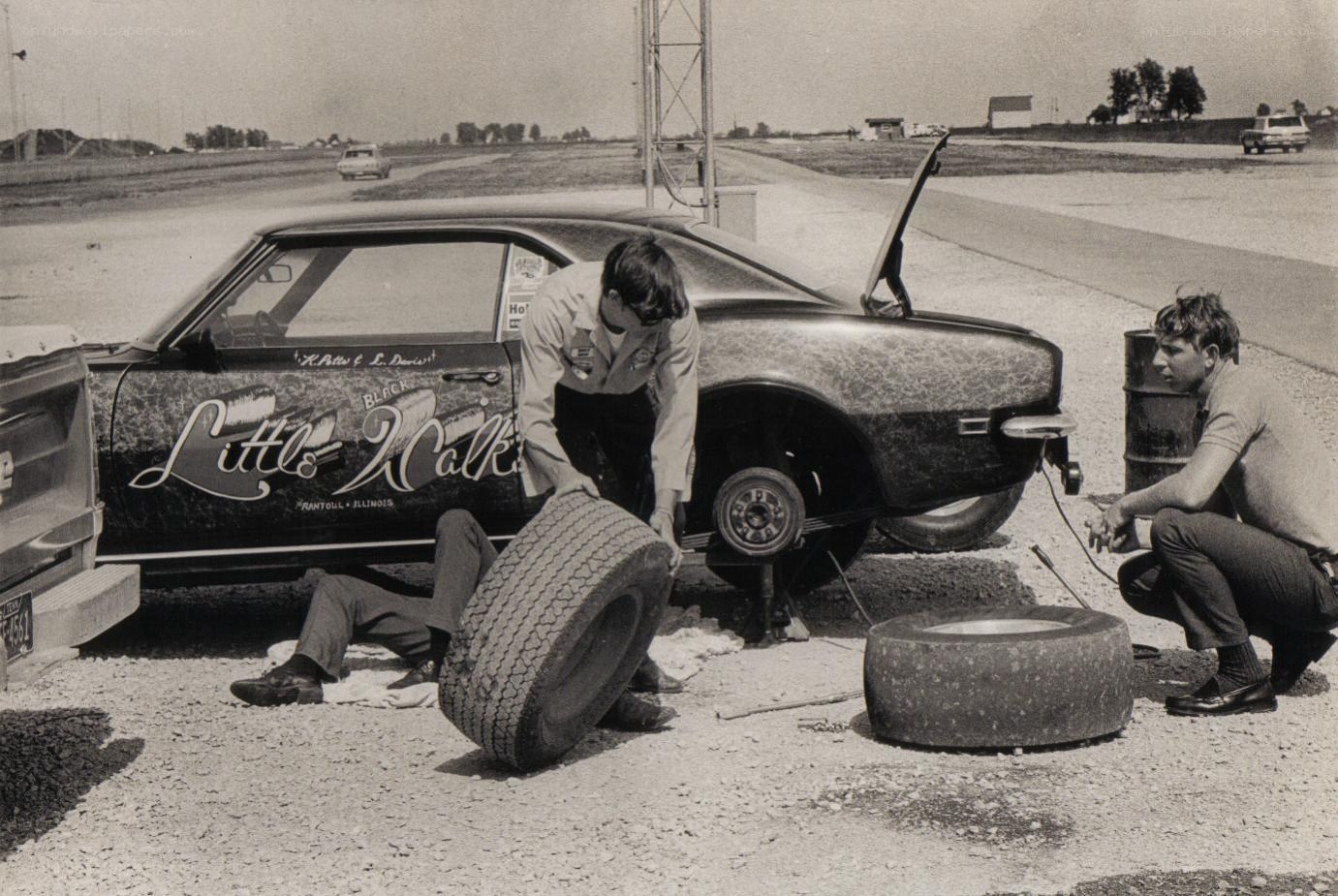 Men changing tire on race car