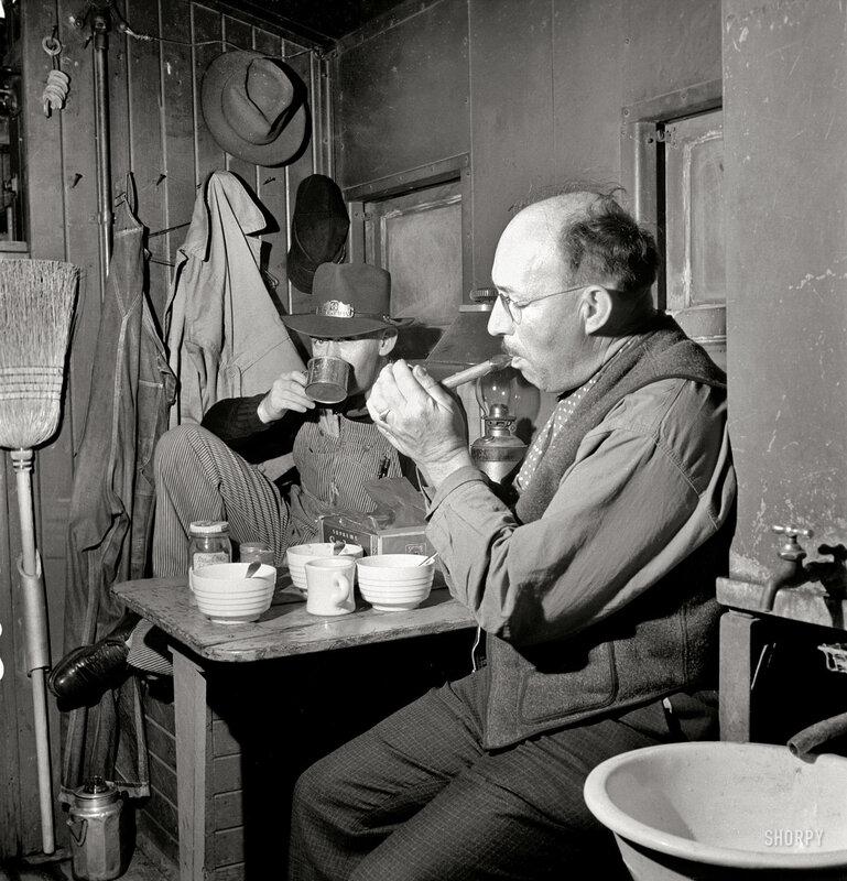 Men eating and smoking in a cabin