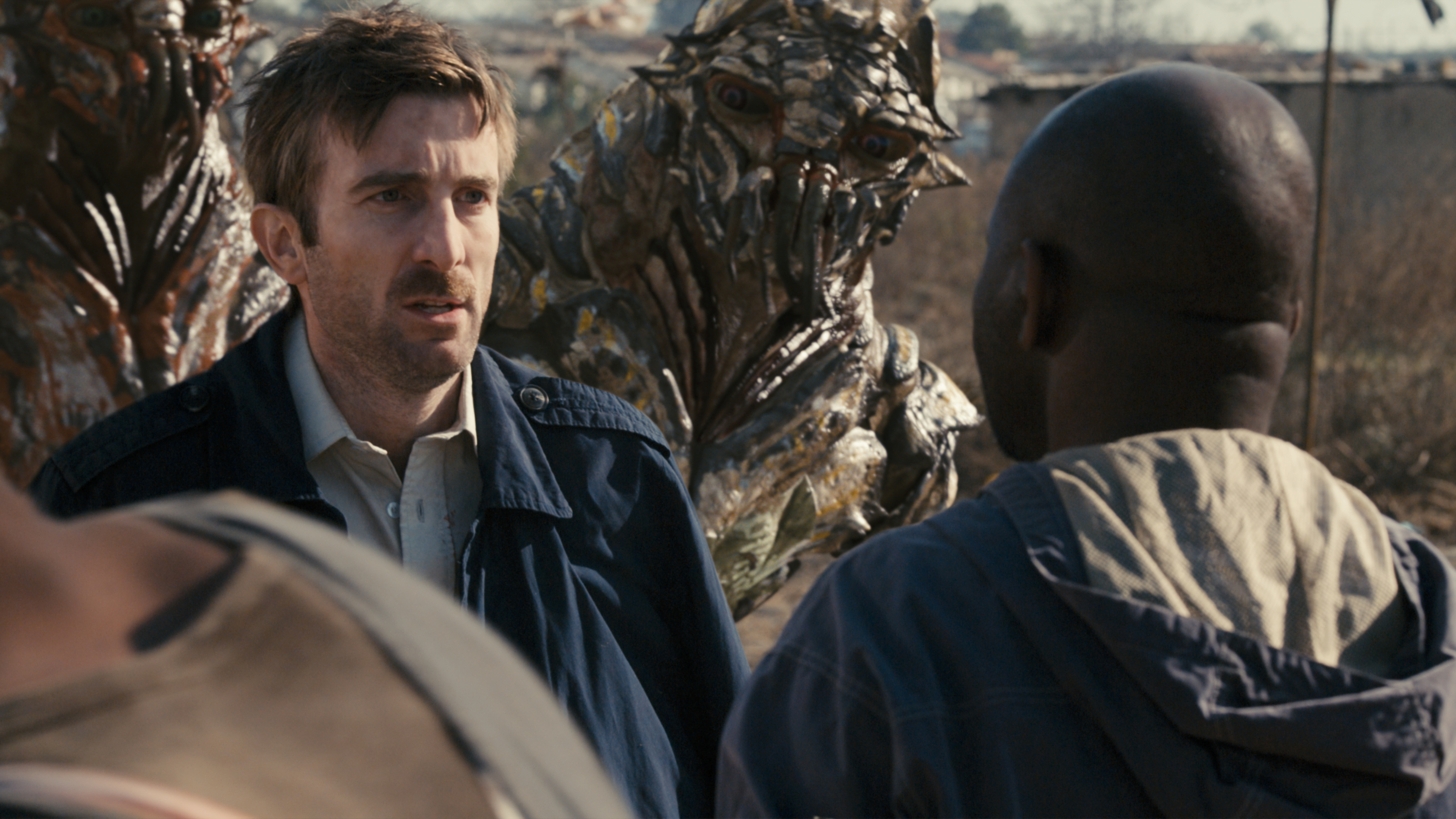 Men facing alien creatures