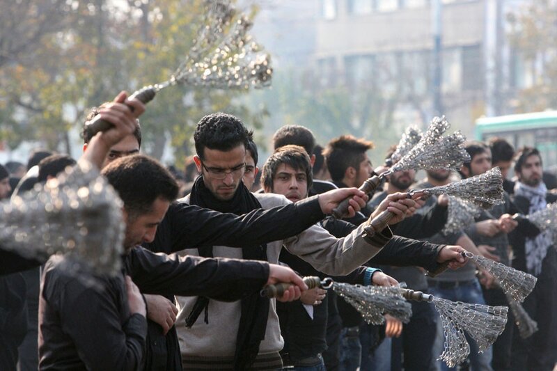Men holding metal whips in protest