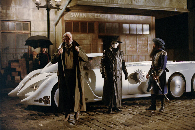 Men in trench coats by vintage car