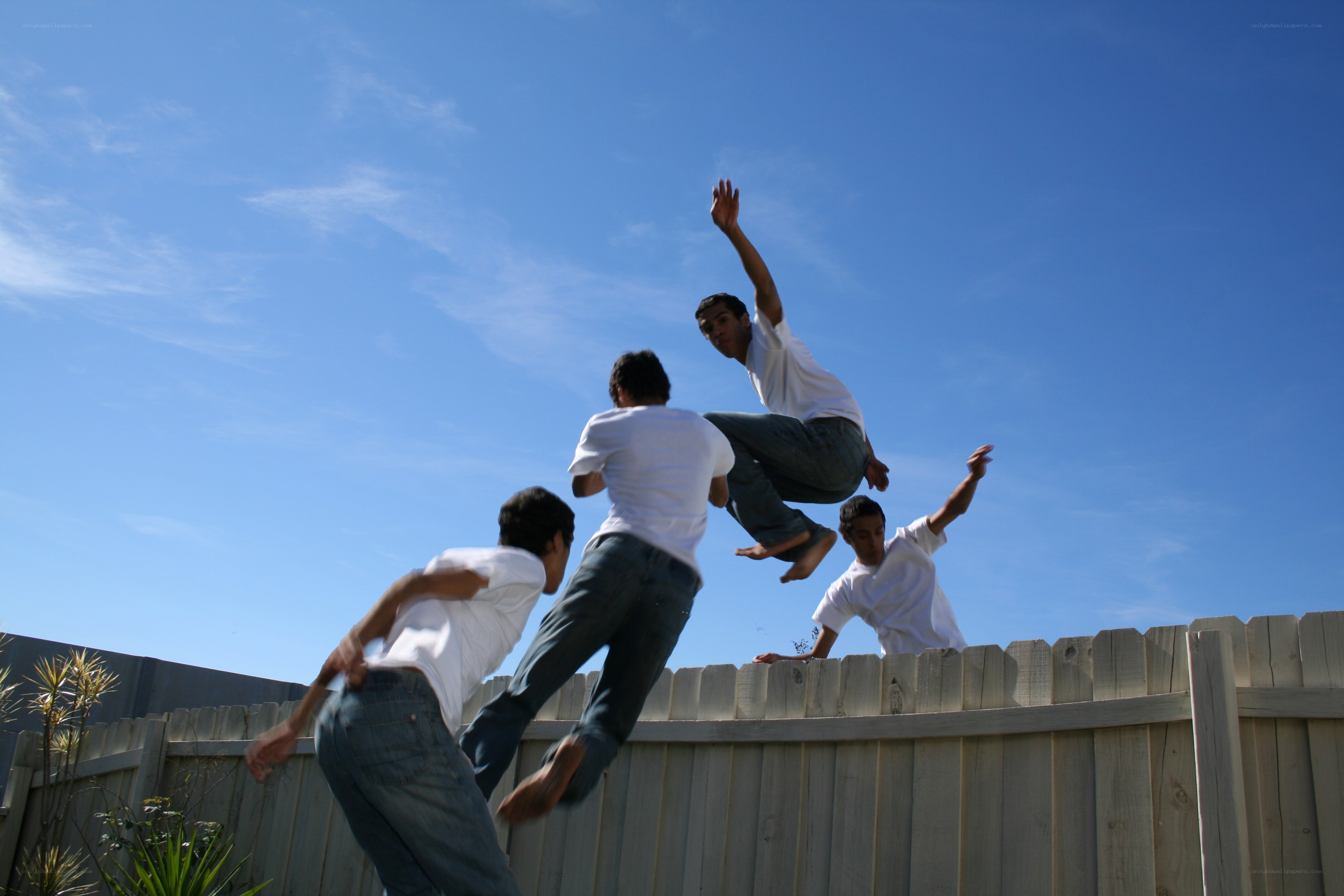 Men jumping over a fence