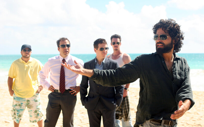 Men on a beach with one gesturing